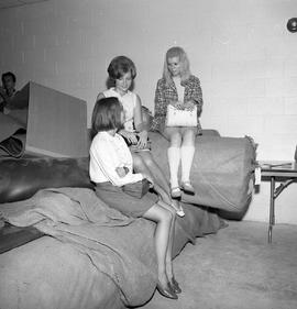 Photograph of women sitting on a carpet roll