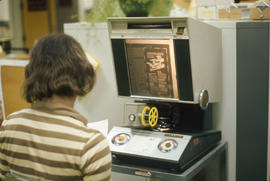 Photograph of a Student Using a Microfilm Reader in the Library