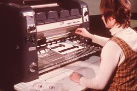 IMC staff using a printing machine : [photograph]