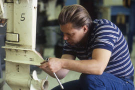 Photograph of a student performing maintenance on outboard motor