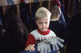 Photograph of a blond haired child with a pair of gloves