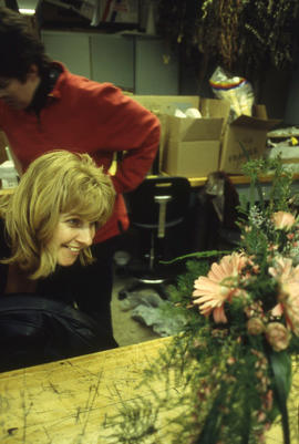 A photograph of an instructor examining a floral arrangement