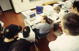 Photograph of students gathered around the computers in the lab