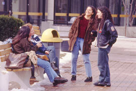 A photograph of students sitting outdoors on a bench