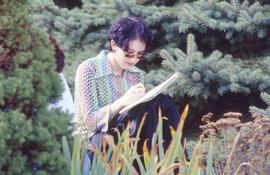 Photograph of a student studying in the arboretum
