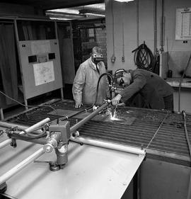 Photograph of a Metal Shop student following a template with a cutter