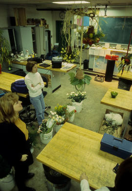 A photograph of students in the Horticulture lab amidst floral displays
