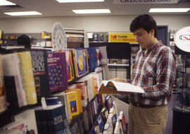 Photograph of an unknown person flipping through a book in the bookshop