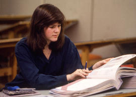 Photograph of a student flipping through a binder for Interior Design