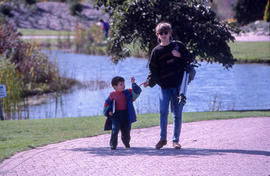 Photograph of a person with camera gear and child walking the arboretum