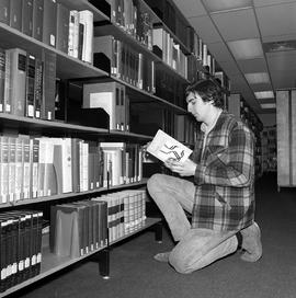 Photograph of a student reading a book in the library in the E building