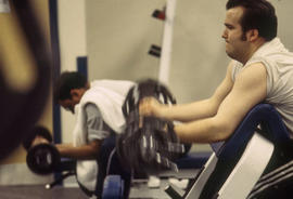 Photograph of two students working out with free weights in the athletic centre.
