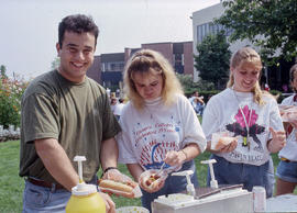 Photograph of three students preparing themselves a hotdog at a college event