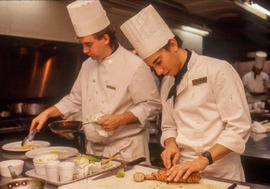 Photograph of two culinary students preparing and plating a dish