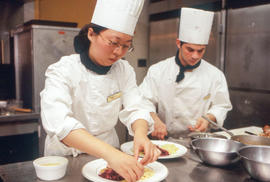 Photograph of two student chefs plating their dishes