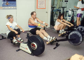 Photograph of three staff members on rowing machines