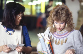 Photograph of two persons looking at bookmarks