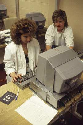 Photograph of a student typing a newspaper article at a computer