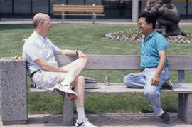 Photograph of Two People Talking on an Outdoor Bench