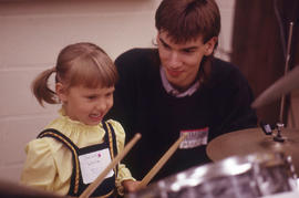 Photograph of a child with two drum sticks in hand