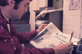 IMC Staff member reading a local newspaper : [photograph]