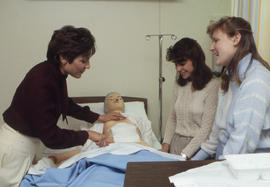 Photograph of a Nursing instructor and students demonstrating application of a sterile bandage on...