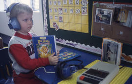 Photograph of a toddler at the daycare centre listening to an audio book