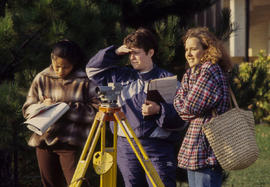 Photograph of three students outside building with surveying equipment