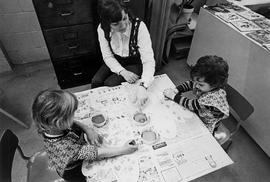 Photograph of an ECE Staff Member Watching Two Toddlers Sponge Painting