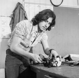 Photograph of a technology student working on an engine