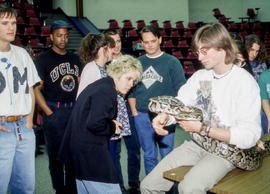 Photograph of students peering at an anaconda held by its handler