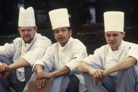 Photograph of three culinary students sitting outdoors in their uniforms