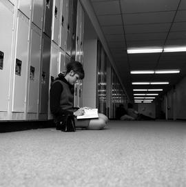 Photograph of an unknown student working by her locker
