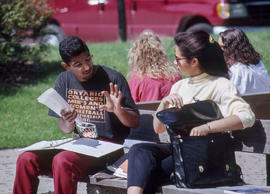 Photograph of students conversing while seated on a bench