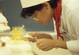 Photograph of a Hospitality student decorating a cake