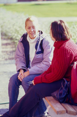 Photograph of students seated outside on a bench