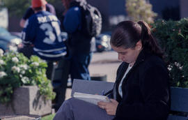 Photograph of a student in a courtyard with a pen and notebook