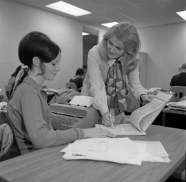 Photograph of a typing instructor assisting a student