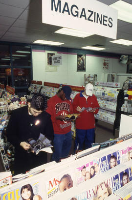 A photograph of three students in the Bookstore reading magazines