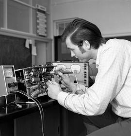 Photograph of an individual repairing electronic test equipment