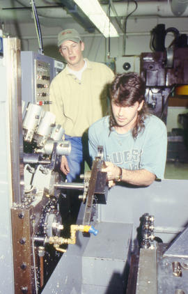 Photograph of students making adjustments to a complex piece of equipment in the Mechanical Engin...