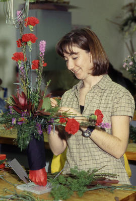 A photograph of a Retail Floriculture student building an arrangement