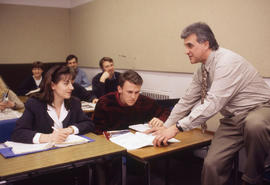 Photograph of a relaxed instructor teaching in a classroom at an unknown location