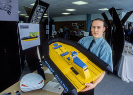 Photograph of a student from the  Industrial Design program holding a model boat
