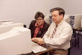 Photograph of an instructor at the computer with a student