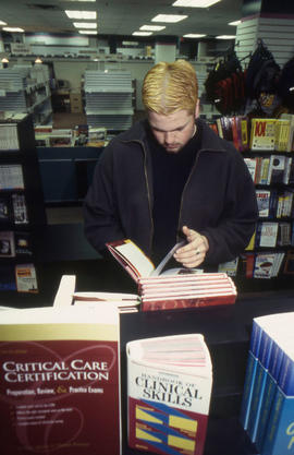 A photograph of a student browsing through books in the Bookstore