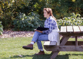 Photograph of a landscape student sitting on a bench in the Arboretum