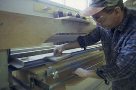 Photograph of a student using a machine to laminate a veneer to a board in the Cabinet Making / W...