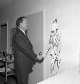 Photograph of instructor Harry Edmunds posing with a display skeleton