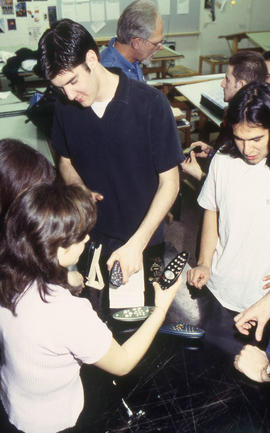 A photograph of Industrial Design students examining each other's designs